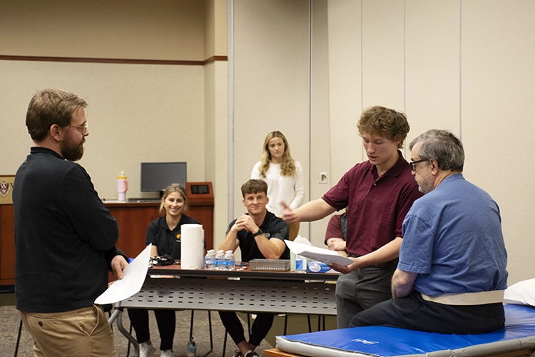 DPT students work with a patient using a grip dynamometer at the Community Clinic