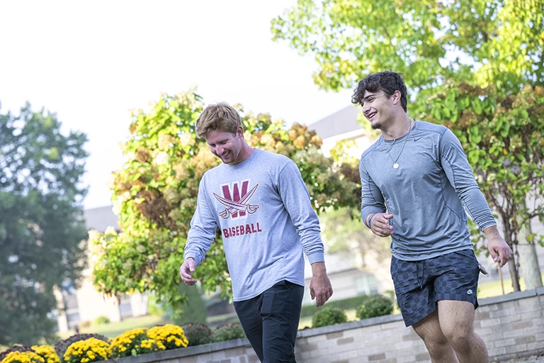 Two students walking on Walsh University's campus in the fall.