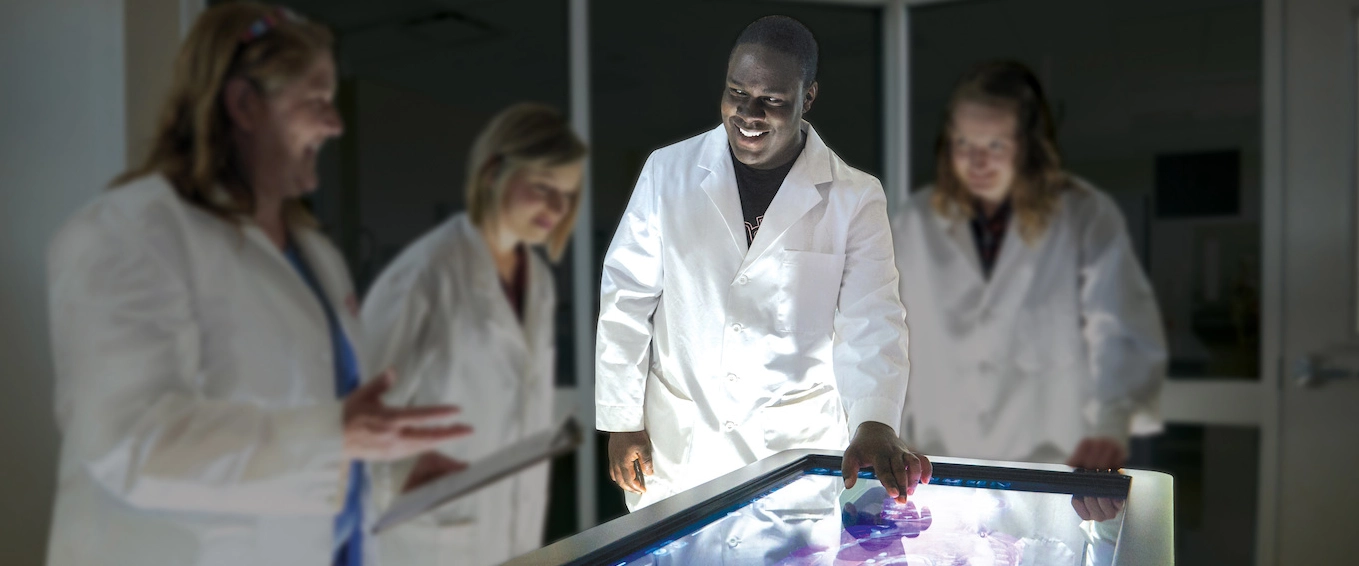 photo of Anatomage table with students in lab coats learning Anatomy