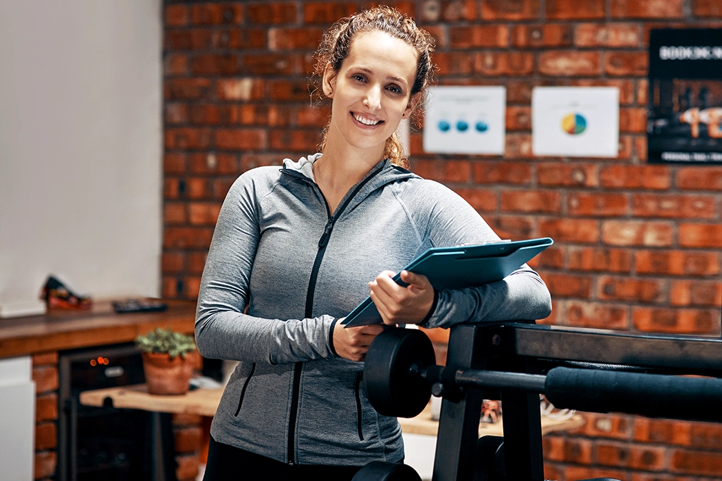 photo of an athletic woman holding a clipboard in a small gym