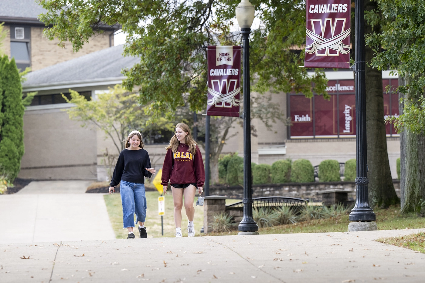 Two students walking across a college campus while having a conversation
