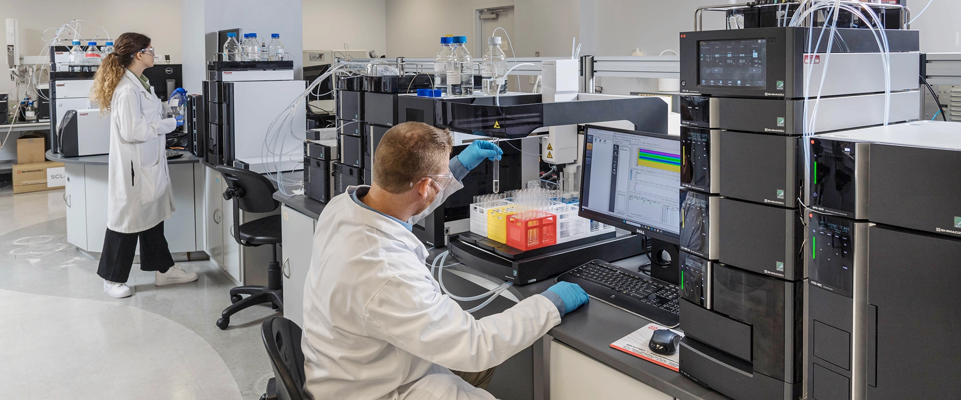 Lab technicians working with Shimadzu HPLC systems in a modern analytical lab.